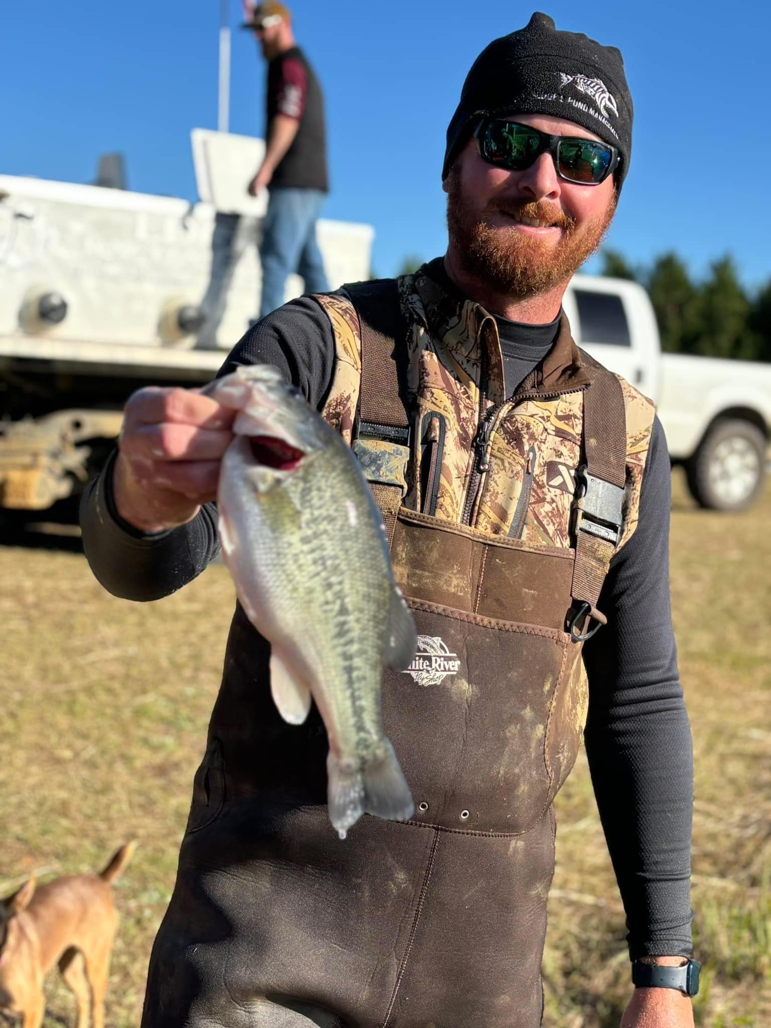 Ethan Edge with Edge's Pond Management and Edge's Aquatic holding a bass in front of a fish truck