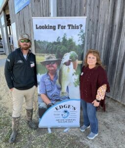 Got bass? Keith Edge holding trophy bass on a poster and kim edge and ethan edge standing beside him